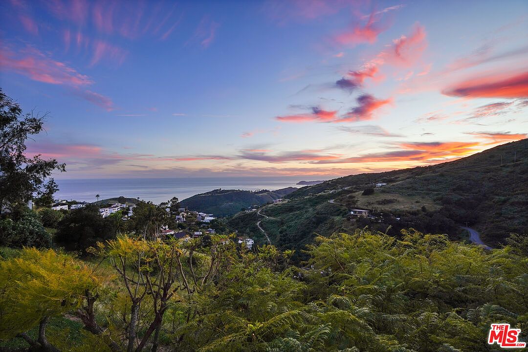 Pink and coral sunset over the Pacific Ocean, viewed from the property with the coastline curving toward Point Dume