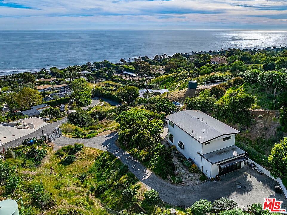 Aerial of the modern hillside home with the Pacific beyond, daytime
