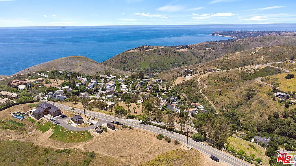Aerial of the canyon neighborhood sweeping toward the Pacific bay and Point Dume